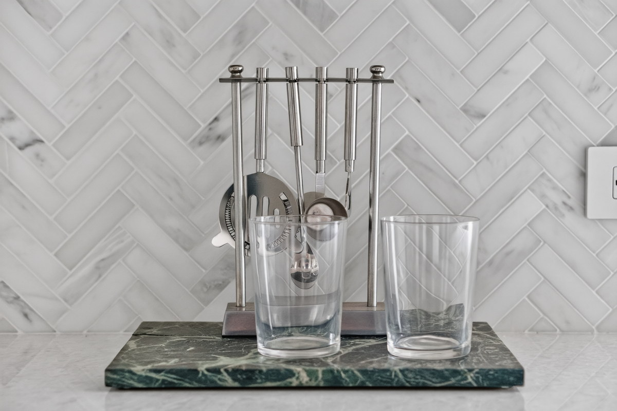 Bar tool set on green marble tray with herringbone backsplash
